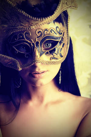 Shot of a sexy woman in a mask over vintage background.の写真素材