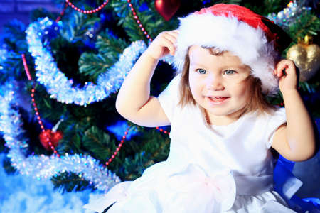 Beautiful child sitting against Christmas decoration.の写真素材