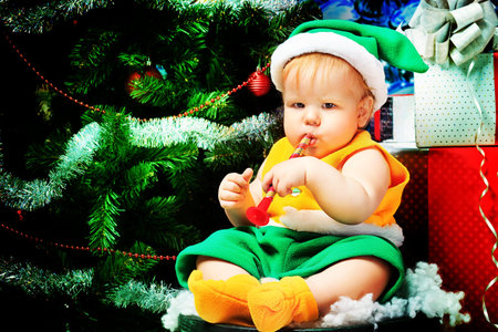 Beautiful child sitting with presents against Christmas background.の写真素材