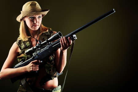 Shot of a sexy woman soldier posing against black background.の写真素材