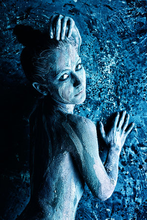 Portrait of an artistic woman painted with clay. Shot in a studio.