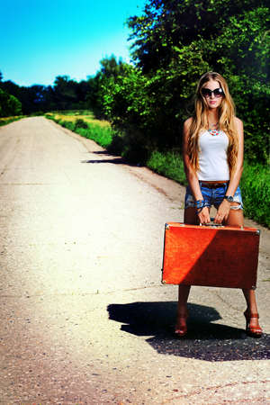 Pretty young woman hitchhiking along a road.の写真素材