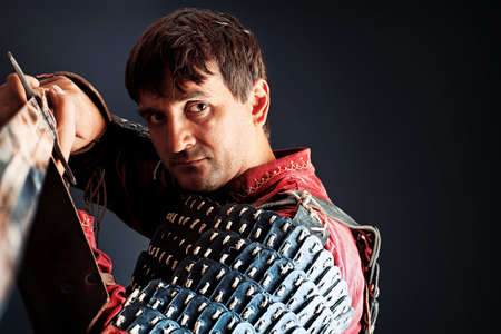 Portrait of a medieval male knight in armor over black background.の写真素材