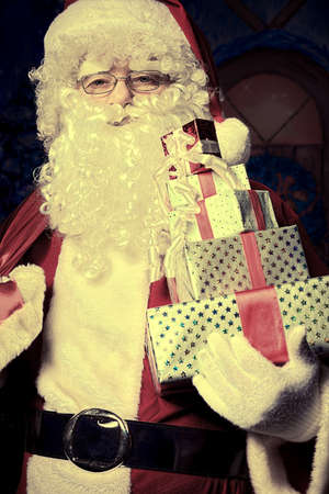 Santa Claus posing with presents over Christmas background.の写真素材