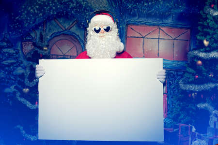 Party Santa Claus holding white board over Christmas background.の写真素材