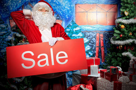 Santa Claus holding sale board over Christmas background.の写真素材