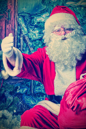 Santa Claus sitting with presents over Christmas background.の写真素材