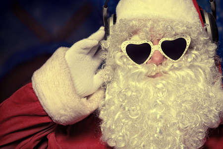 Santa Claus is listening to music in headphones. Christmas.の写真素材