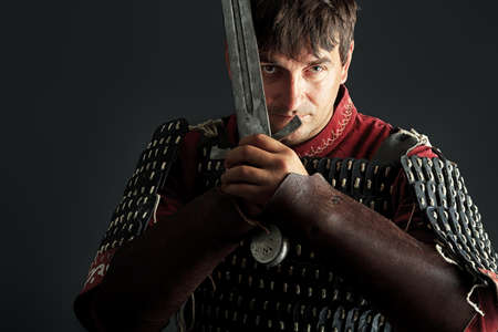 Portrait of a medieval male knight in armor over black background.の写真素材