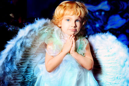 Beautiful little angel girl over Christmas background.の写真素材