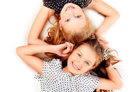 Portrait of two little girls sisters posing at studio  Isolated over white の写真素材