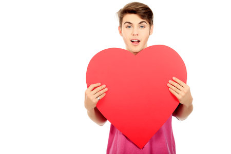 Happy young man posing with red heart. Isolated over white background.