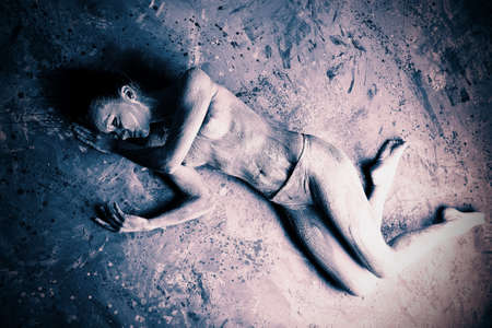 Portrait of an artistic woman painted with clay. Shot in a studio. の写真素材