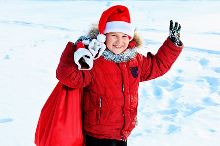 Happy boy standing with Christmas sack of presents outdoor. の写真素材