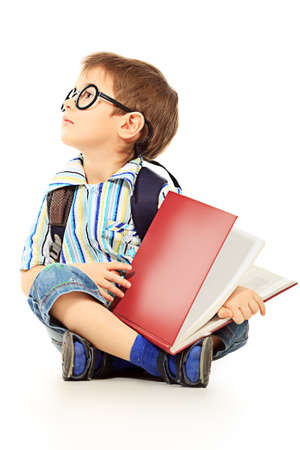Portrait of a little boy in spectacles reading a book. Isolated over white background.の写真素材