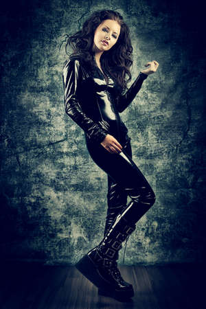 Fashion shot of a woman in black glossy overall and platform boots.の写真素材