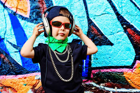 Portrait of a trendy little boy  with headphones outdoors.の写真素材