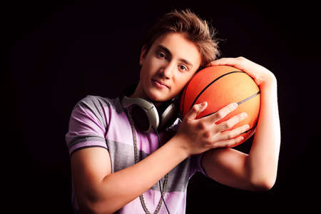 Young sportsman basketball player posing with ball  Over black background の写真素材