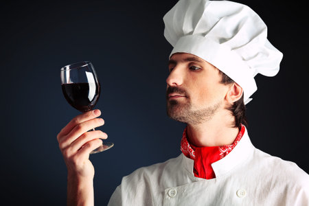 Portrait of a man cook holding a glass of red wine. Shot in a studio.の写真素材