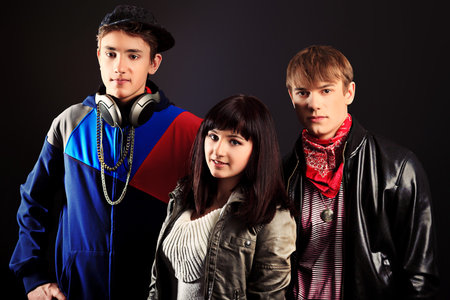 Group of stylish young people posing over black background. 