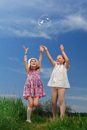 Two happy girls playing with big bubbles in a park.の写真素材