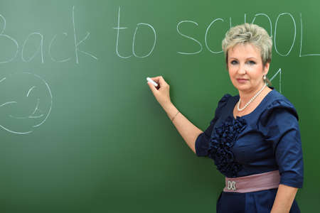 Portrait of a smiling teacher writing on a blackboard.の写真素材