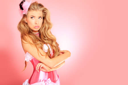 Portrait of a charming blonde woman posing in studio over pink background.の写真素材