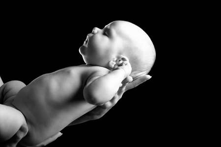 Mother's hands tenderly hold their newborn baby.の写真素材