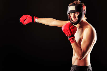 Portrait of a handsome boxer in red gloves and helmet  posing at studio.の写真素材