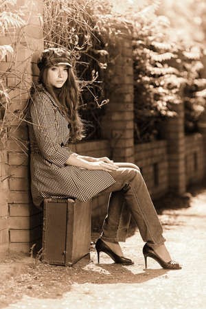 Beautiful young woman with old suitcase walking down the street.の写真素材