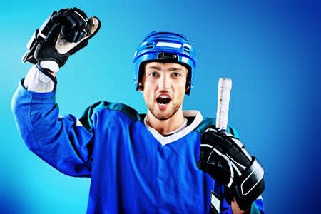 Portrait of a handsome ice-hockey player with hockey stick. Studio shot.の写真素材