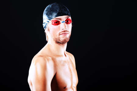 Portrait of a man professional  swimmer posing at studio over black background.の写真素材