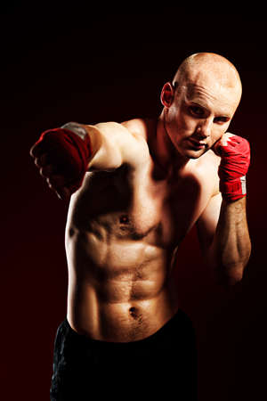 Portrait of a muscular boxer in red gloves posing at studio.の写真素材