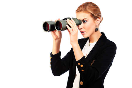 Beautiful young woman in business suit looking through binocular. Isolated over white background.の写真素材