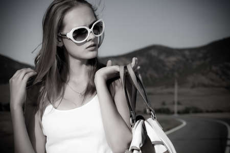 Beautiful young woman posing on a road over picturesque landscape.の写真素材