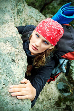 Beautiful woman alpinist is climbing on a mountain.の写真素材