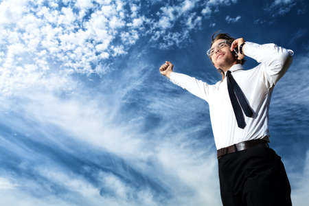 Successful business man standing over blue sky and purposefully looking away.の写真素材