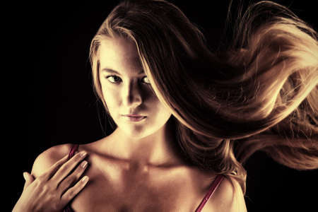 Portrait of a sexual woman with streaming hair posing in lingerie over black background.の写真素材