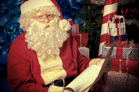 Santa Claus posing with a list of presents over Christmas background.