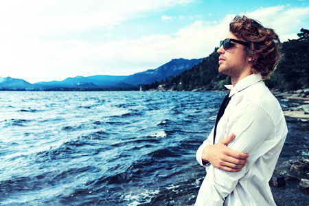 Handsome business man standing on a seaside and looking into the distance.