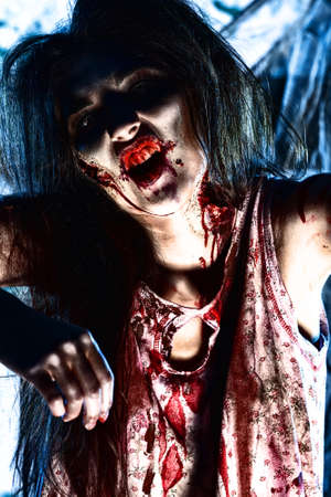 Bloodthirsty zombi standing at the night cemetery in the mist and moonlight.の写真素材