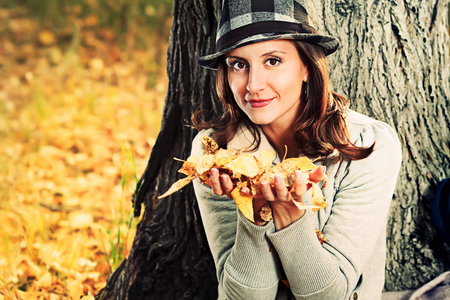 Happy young woman having a rest outdoor in the autumn park.の写真素材