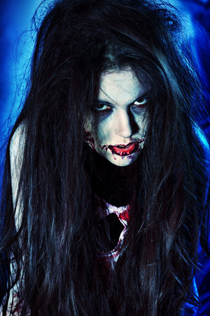 Bloodthirsty zombi standing at the night cemetery in the mist and moonlight.