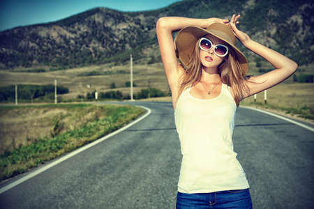 Beautiful young woman posing on a road over picturesque landscape.の写真素材