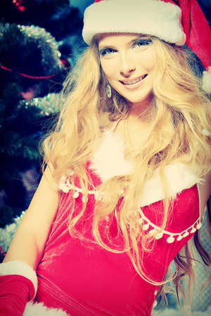 Beautiful young woman in Santa Claus clothes over Christmas background.の写真素材