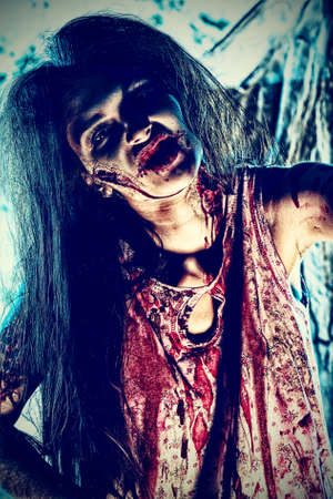 Bloodthirsty zombi standing at the night cemetery in the mist and moonlight.の写真素材