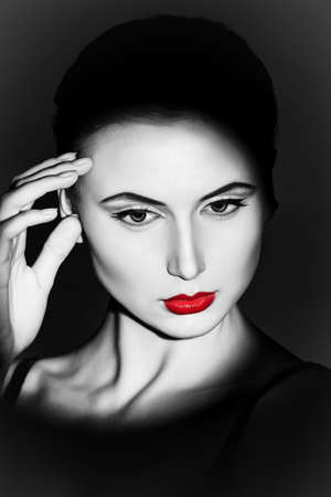 Portrait of a charming young woman over dark background. Light and shadow.の写真素材