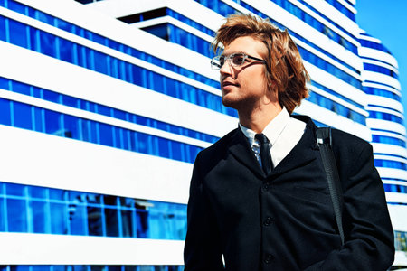 Young business man standing in the big city and purposefully looking away.