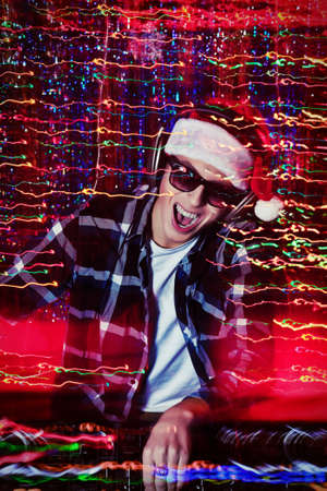 DJ man mixing up some Christmas cheer  Disco lights in the background  の写真素材
