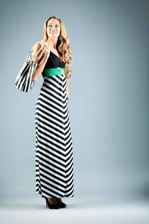 Charming fashionable young woman posing over gray background.の写真素材